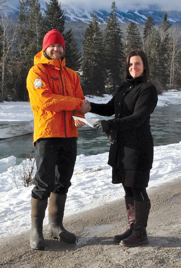 Isabelle Thibeault of Chatter Creek lodge hands over a donation to Nick Comstock