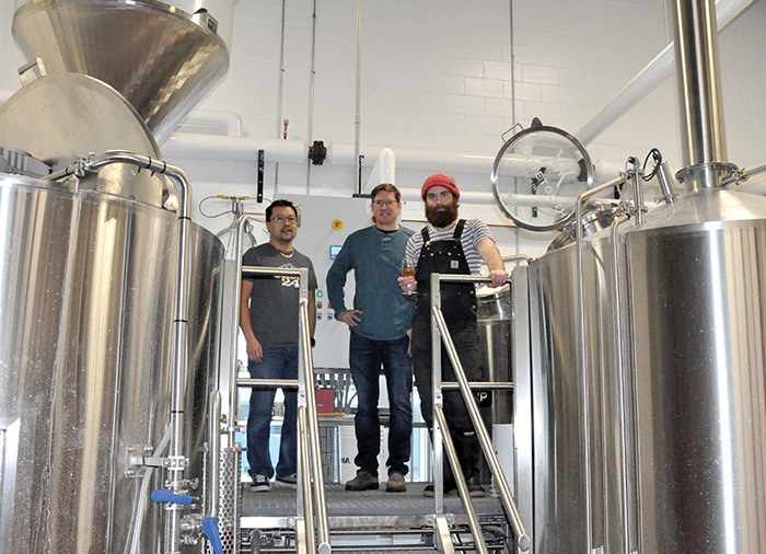 Whitetooth Brewing Company owners Mark Nagao and Kent Donaldson stand in the brewing room with brewmaster Evan Cronshaw