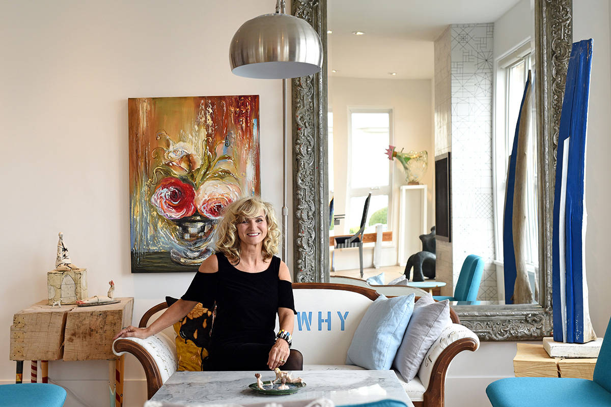 Artist Elka Nowika in her home with one of paintings (at left) on the wall behind her. (Don Denton/Boulevard)