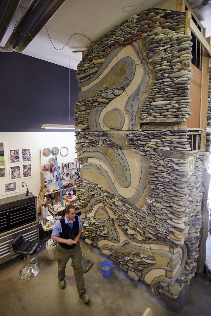 Artist Andreas Kunert is dwarfed by a fireplace currently under construction at the Ancient Art of Stone studio and store front in Duncan. This is only two thirds of the fireplace, there is a third piece that will be added to the top. Don Denton photography