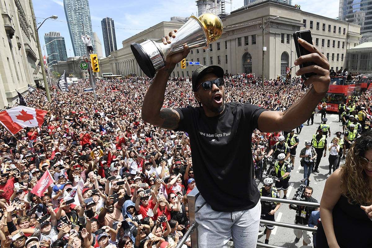 Toronto Raptors forward Kawhi Leonard takes a selfie holding his playoffs MVP trophy during the NBA basketball championship team’s victory parade in Toronto, Monday, June 17, 2019. (Frank Gunn/The Canadian Press via AP)