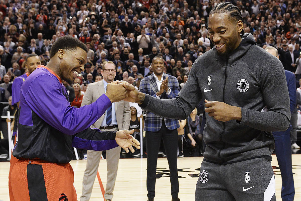 Former Toronto Raptors and now LA Clippers forward Kawhi Leonard, right, receives his 2019 NBA championship ring from Raptors’ Kyle Lowry prior to NBA basketball action in Toronto on Wednesday, Dec. 11, 2019. THE CANADIAN PRESS/Nathan Denette