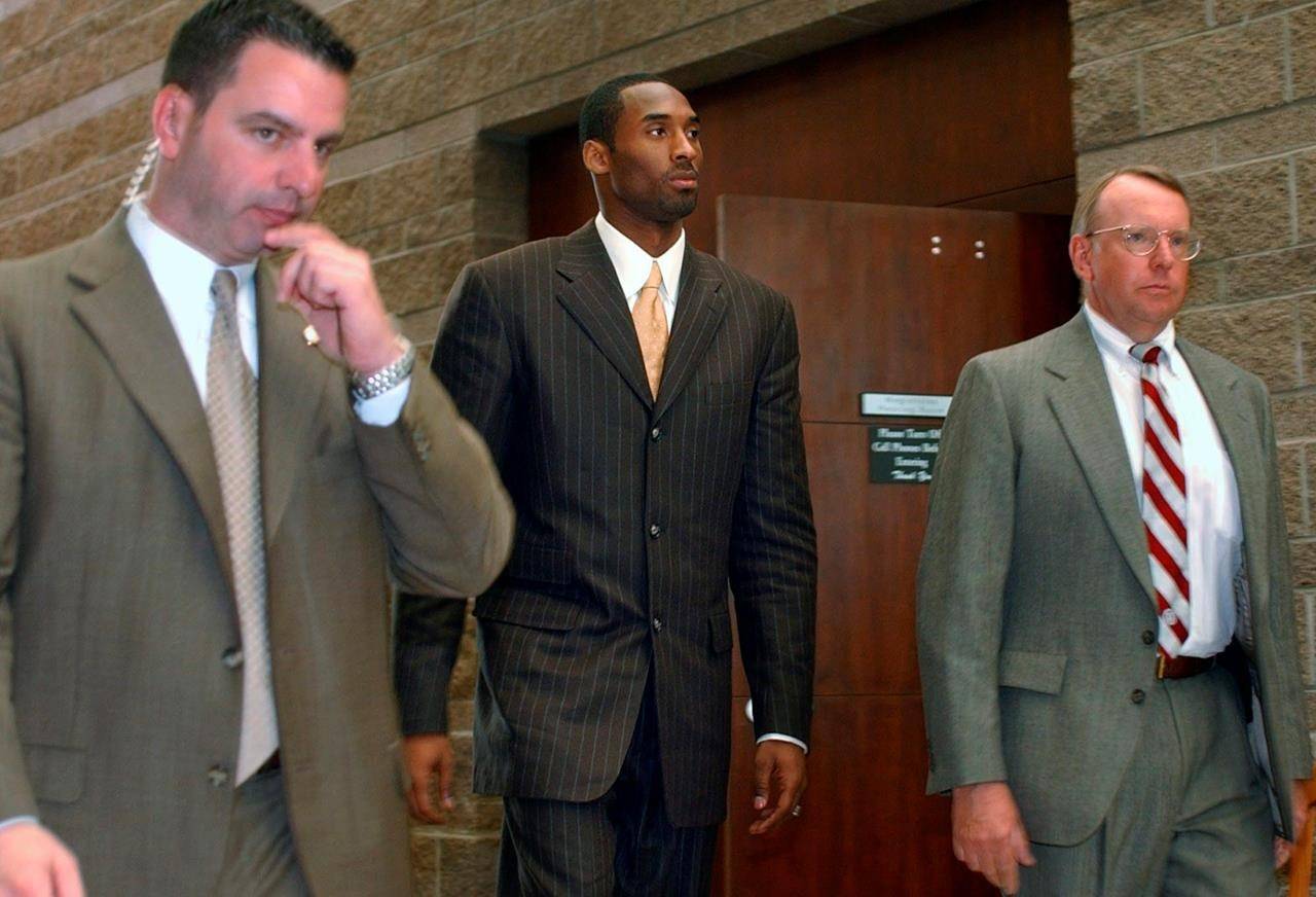 FILE - In this Wednesday, March 24, 2004, file photo, Los Angeles Lakers’ Kobe Bryant, center, walks out of a holding area as he prepares to leave for a lunch break from proceedings in his sexual assault case as members of his security team accompany him, in Eagle, Colo. Some argued that there was no need to dredge up accounts of the 2003 rape allegation against Bryant when he died suddenly Sunday, Jan. 26, 2020. Others viewed it as another example of an icon being given a pass because he was a successful athlete. (AP Photo/Ed Andrieski, File)