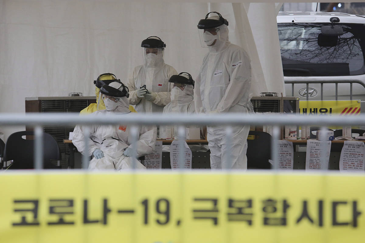 Medical staff wearing protective suits wait to take samples from drivers with symptoms of the coronavirus at a “drive-through” virus test facility in Goyang, South Korea, Sunday, March 1, 2020. The coronavirus has claimed its first victim in the United States as the number of cases shot up in Iran, Italy and South Korea and the spreading outbreak shook the global economy. The signs read “Let’s overcome the coronavirus.”(Kim Hyun-tae/Yonhap via AP)