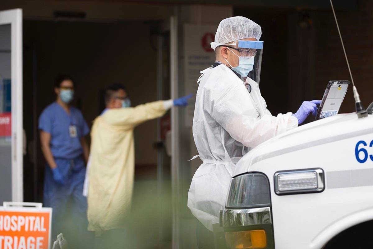 Ambulance paramedic in full protective gear works outside Lion’s Gate Hospital, March 23, 2020. Gowns, masks and gloves are being used rapidly in the COVID-19 pandemic. (The Canadian Press)