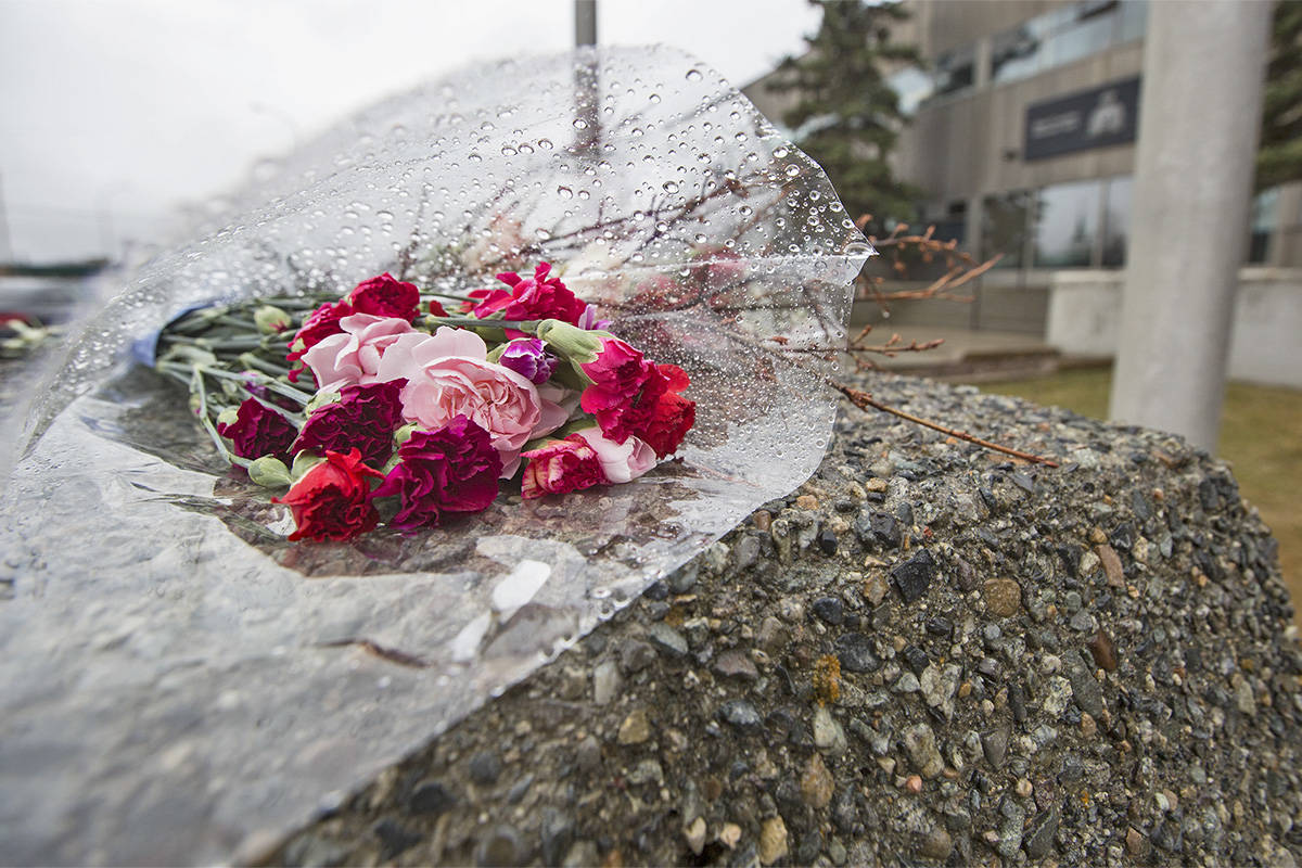 Flowers lay in the rain below half mast flags at the RCMP headquarters in Whitehorse on April 23, in honour of the officer killed on April 19 in Nova Scotia. (Crystal Schick/Yukon News)