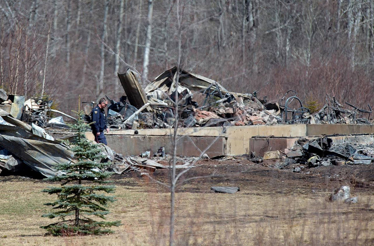 An RCMP investigator inspects a house destroyed by fire at the residence of Alanna Jenkins and Sean McLeod, both corrections officers, in Wentworth Centre, N.S. on Monday, April 20, 2020. THE CANADIAN PRESS/Andrew Vaughan