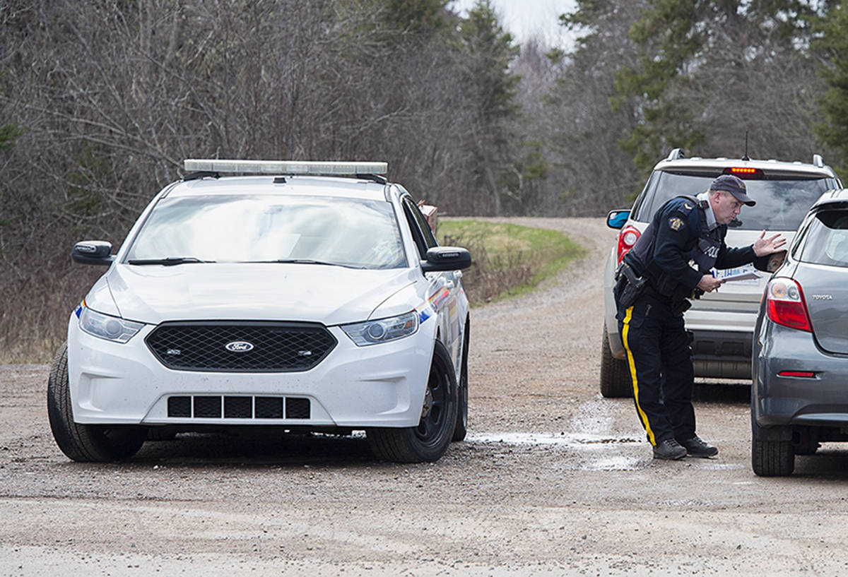 An RCMP officer talks with a local resident before escorting them home at a roadblock in Portapique, N.S. on Wednesday, April 22, 2020. RCMP say at least 22 people are dead after a man who at one point wore a police uniform and drove a mock-up cruiser, went on a murder rampage in Portapique and several other Nova Scotia communities. THE CANADIAN PRESS/Andrew Vaughan