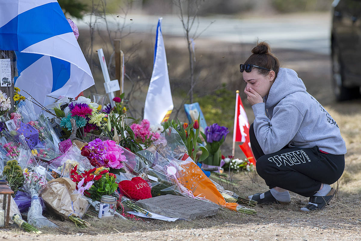 A woman pays her respects at a roadside memorial on Portapique Road in Portapique, N.S. on Friday, April 24, 2020. At least 22 people are dead after a man, who at one point wore a police uniform and drove a mock-up cruiser, went on a murder rampage in Portapique and several other Nova Scotia communities. THE CANADIAN PRESS/Andrew Vaughan