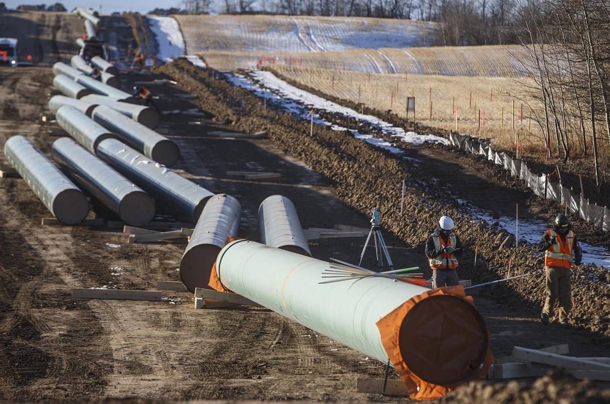Workers survey around pipe to start of right-of-way construction for the Trans Mountain Expansion Project, in Acheson, Alta., Tuesday, Dec. 3, 2019. Energy projects like an LNG Canada export terminal and the Trans Mountain pipeline expansion may face short-term setbacks but the pandemic and oil price crash shouldn’t threaten their long-term viability, economists say. THE CANADIAN PRESS/Jason Franson