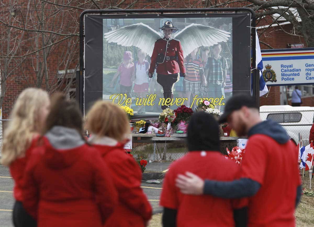 Mourners, asked to wear red on Friday, are seen near a mural dedicated to slain Royal Canadian Mounted Police Const. Heidi Stevenson, during a province-wide, two-minutes of silence for the 22 victims of last weekend’s shooting rampage, in front of the RCMP detachment in Cole Harbour, Nova Scotia, Friday, April 24, 2020. (Tim Krochak/The Canadian Press via AP)                                Mourners, asked to wear red on Friday, are seen near a mural dedicated to slain Royal Canadian Mounted Police Const. Heidi Stevenson, during a province-wide, two-minutes of silence for the 22 victims of last weekend’s shooting rampage, in front of the RCMP detachment in Cole Harbour, Nova Scotia, Friday, April 24, 2020. (Tim Krochak/The Canadian Press via AP)