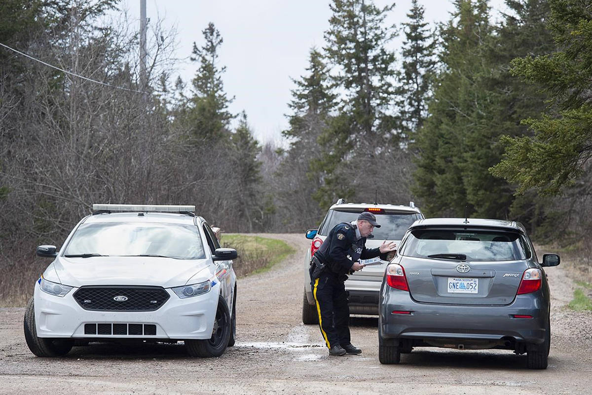 An RCMP officer talks with a local resident before escorting them home at a roadblock in Portapique, N.S. on Wednesday, April 22, 2020. THE CANADIAN PRESS/Andrew Vaughan
