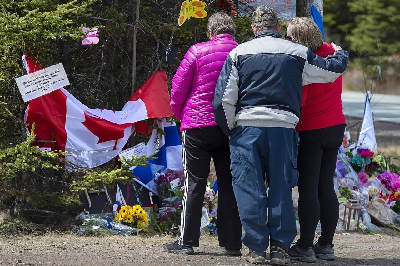 A family pays their respects to victims of the mass killings at a checkpoint on Portapique Road in Portapique, N.S. on Friday, April 24, 2020. As pressure mounts on the federal and Nova Scotia governments to call an inquiry into one of the worst mass killings in Canadian history, the country’s leading scholar on inquiries says Ottawa and the province should do the right thing and work together on a joint inquest. THE CANADIAN PRESS/Andrew Vaughan