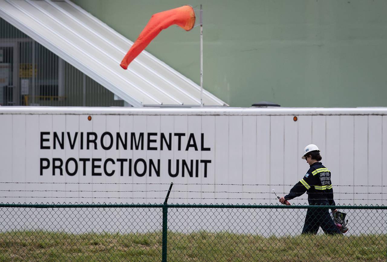 An emergency response worker carries an air monitoring device at the site of a crude oil spill at a Trans Mountain Pipeline pump station in Abbotsford, on Sunday, June 14, 2020. Trans Mountain estimates as much as 1,195 barrels of light crude spilled from the pipeline pumping station. While an investigation is ongoing, the Crown-owned company said in a statement the cause of the spill appears to be related to a fitting on a one-inch, or 2.5-centimetre, piece of pipe. THE CANADIAN PRESS/Darryl Dyck
