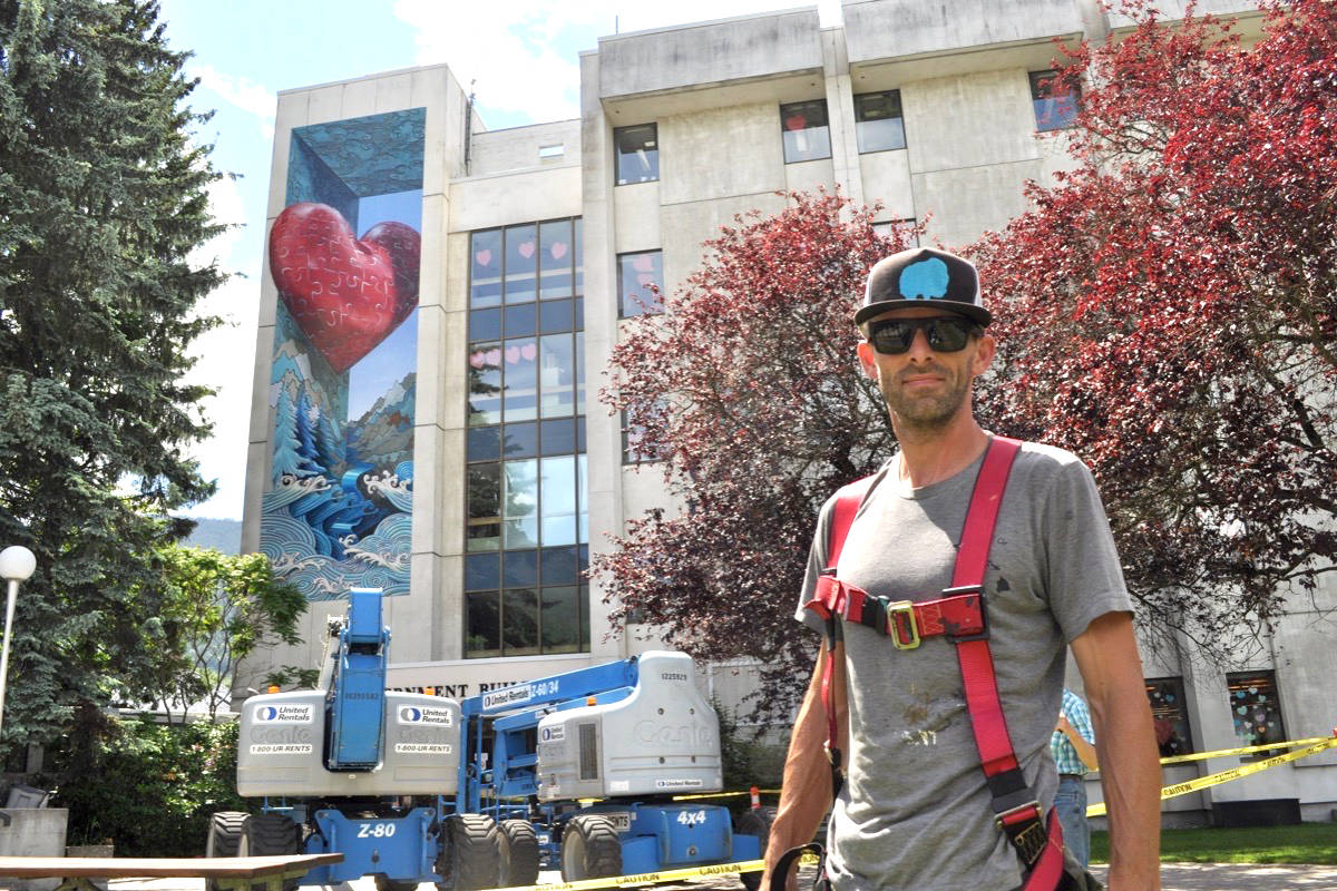 Artist Tyler Toews stands by his mural that now adorns Nelson City Hall. Photo: Tyler Harper
