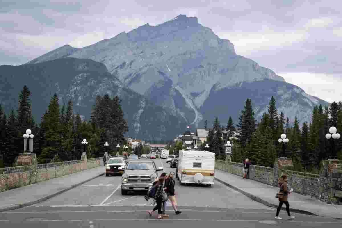 FILE – People walk across a street in Banff, Alta., in Banff National Park, Friday, July 21, 2017. THE CANADIAN PRESS/Jeff McIntosh