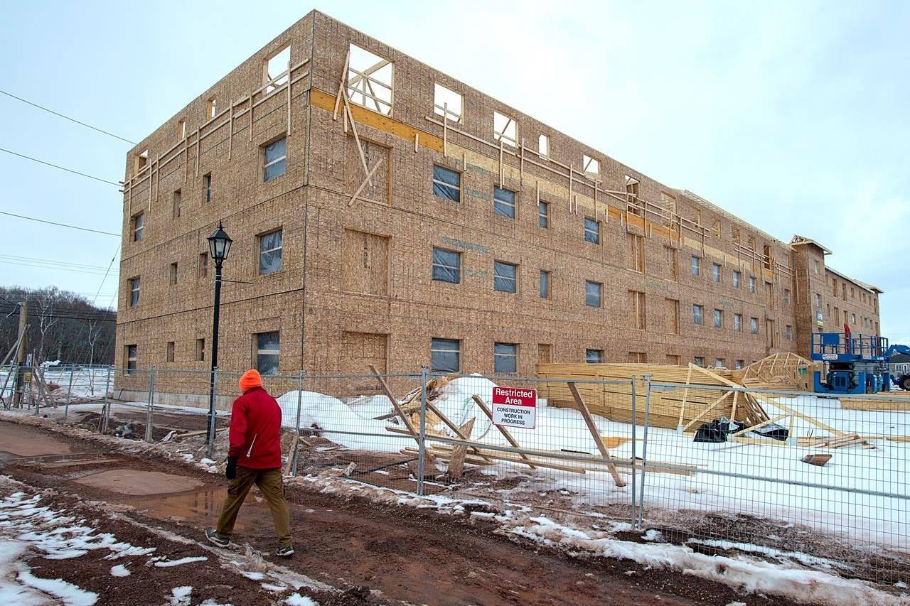 A man walks past an affordable housing complex, being constructed in Charlottetown’s Hillsborough Park area, on Saturday, February 29, 2020. Seven provinces have signed on to a federal rent assistance program created as part of the national housing strategy, three more than the Liberals have announced, newly released documents show. THE CANADIAN PRESS/Andrew Vaughan