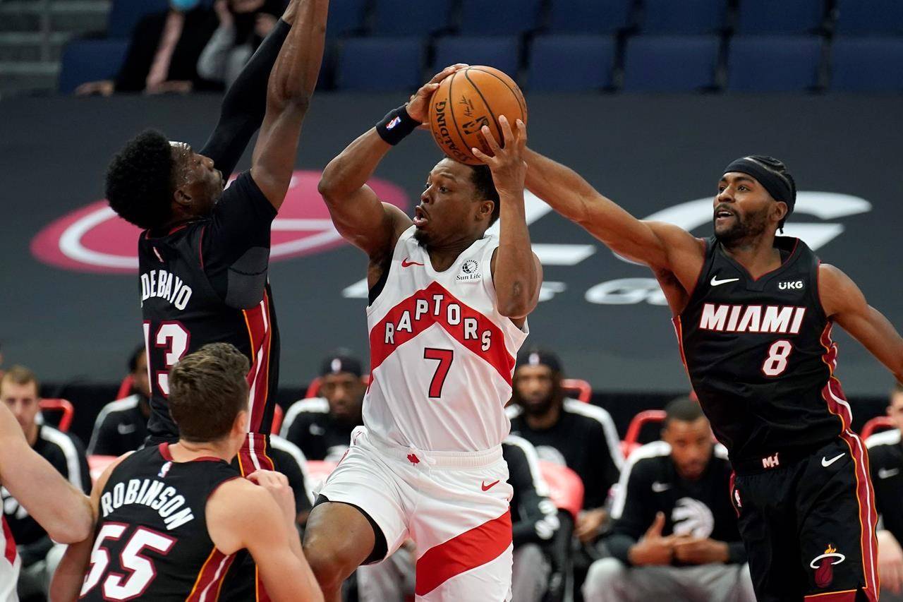 Toronto Raptors guard Kyle Lowry (7) goes to the basket between Miami Heat forward Bam Adebayo (13) and forward Maurice Harkless during the first half of an NBA preseason basketball game Friday, Dec. 18, 2020, in Tampa, Fla. The Raptors are playing their home games in Tampa as a result of Canada’s strict travel regulations stemming from the coronavirus pandemic. (AP Photo/Chris O’Meara)