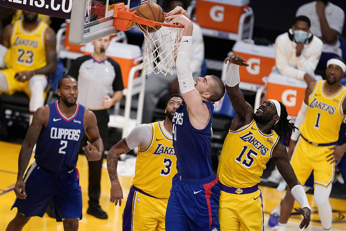 Los Angeles Clippers center Ivica Zubac, center, dunks past Los Angeles Lakers forward Montrezl Harrell (15) during the second half of an NBA basketball game Tuesday, Dec. 22, 2020, in Los Angeles. (AP Photo/Marcio Jose Sanchez)