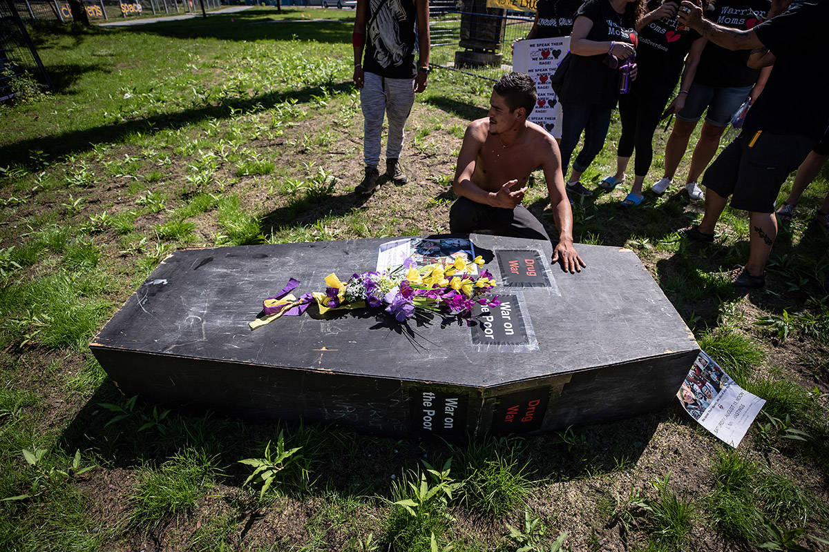 A man pauses at a coffin after carrying it during a memorial march to remember victims of overdose deaths in Vancouver on Saturday, August 15, 2020. THE CANADIAN PRESS/Darryl Dyck