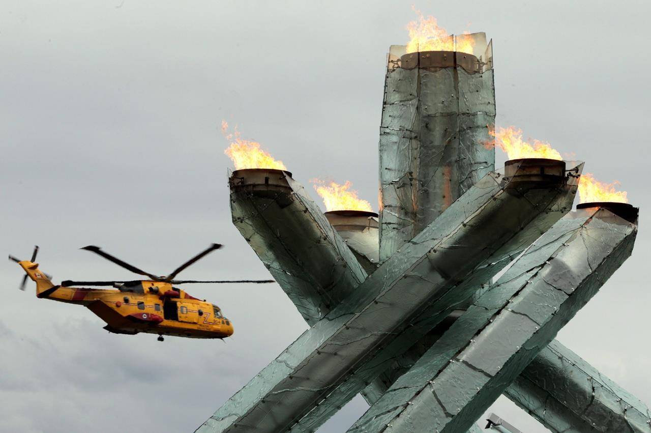 A Canadian Forces CH-149 Cormorant helicopter flies past the Olympic cauldron as it burns during Canada Day festivities in Vancouver, B.C., Thursday July 1, 2010. The owner of a scallop trawler that caught fire at sea south of Yarmouth, N.S., Tuesday night says all crew members are safely off the boat. THE CANADIAN PRESS/Darryl Dyck