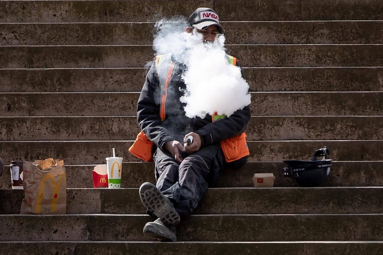 A construction worker exhales after using a vaping device while eating lunch on the steps at Robson Square, in Vancouver, on Monday, March 8, 2021. THE CANADIAN PRESS/Darryl Dyck