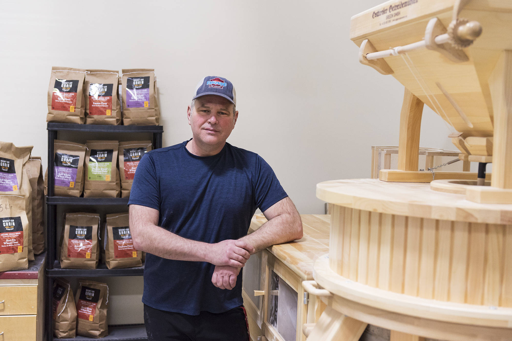 Salmon Arm entrepreneur David Allard stands next to the stone mill he uses to produce organic flours for his Mount Ida Grain Company, which he uses for the pizzas produced by his other business, the Westgate Food Hub, both of which are located in the Westgate Public Market, on Thursday, March 18. 2021. (Lachlan Labere-Salmon Arm Observer)
