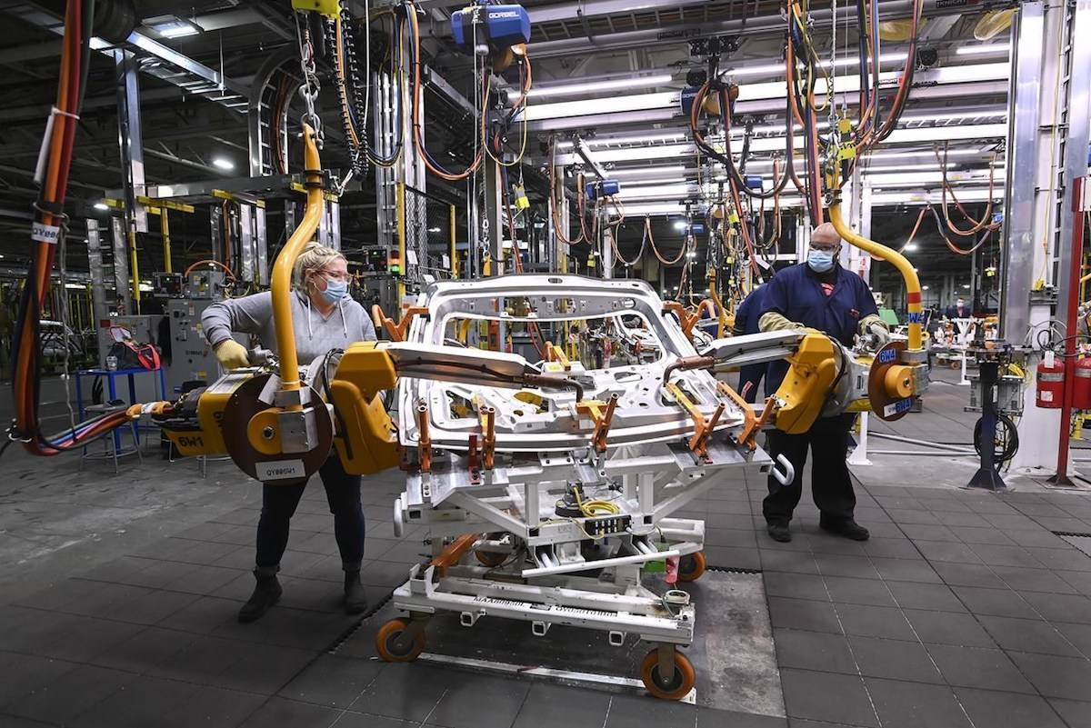 GM workers use human assistance automation to weld vehicle doors at the General Motors assembly plant during the COVID-19 pandemic in Oshawa, Ont., on Friday, March 19, 2021. THE CANADIAN PRESS/Nathan Denette