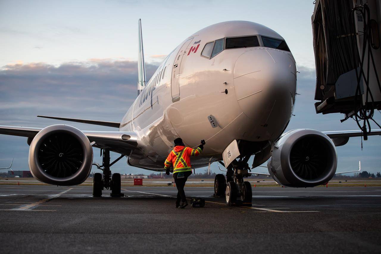 A ground worker approaches a WestJet Airlines Boeing 737 Max aircraft after it arrived at Vancouver International Airport in Richmond, B.C., on Thursday, January 21, 2021. THE CANADIAN PRESS/Darryl Dyck