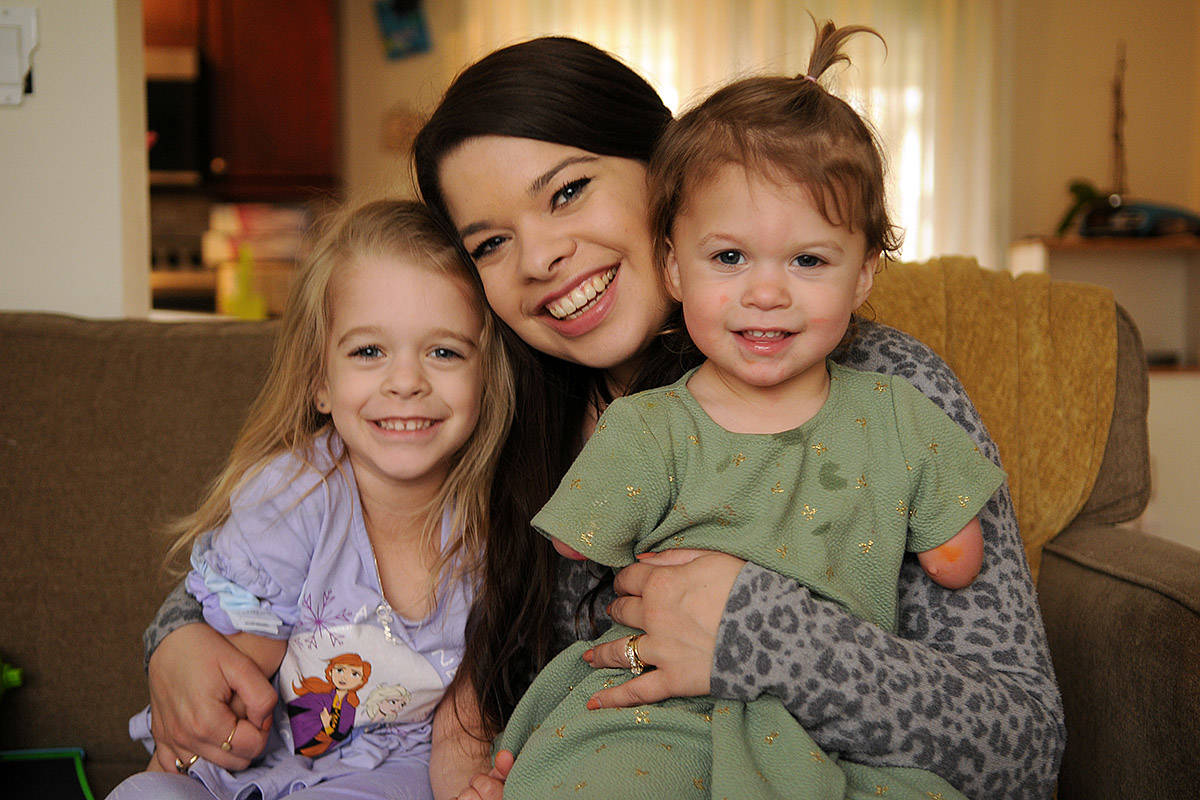 Two-year-old Ivy McLeod, seen here on April 9, 2021 with four-year-old sister Elena and mom Vanessa, was born with limb differences. The family, including husband/dad Sean McLeod, is looking for a family puppy that also has a limb difference. (Jenna Hauck/ Chilliwack Progress)