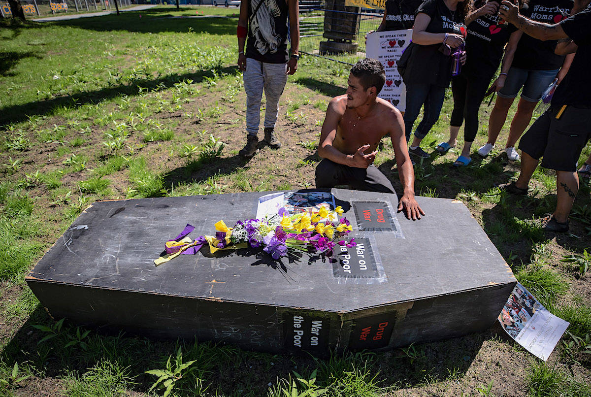 A man pauses at a coffin after carrying it during a memorial march to remember victims of overdose deaths in Vancouver. THE CANADIAN PRESS/Darryl Dyck