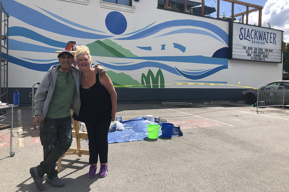 Artist Siya Ghaffari takes a break with friend and fellow painter Renee Matheson before going back to paint the seascape mural that now covers the wall on the back of Slackwater Brewing. (Monique Tamminga Western News)