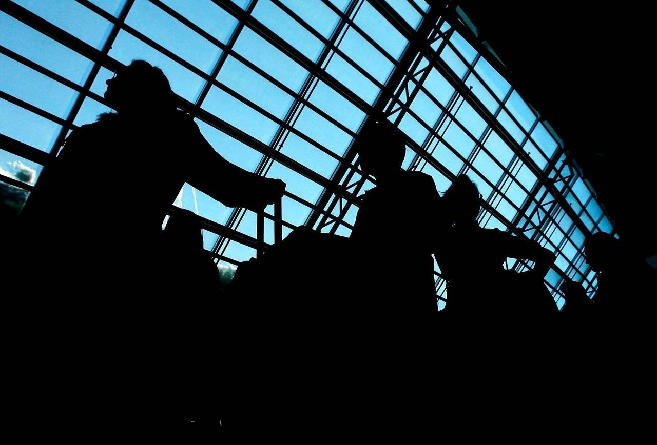 People are silhouetted as they wait in line to check their luggage on Friday, March 9, 2007 at Pearson International Airport in Toronto for March Break. A new report by Statistics Canada says job losses due to the COVID-19 pandemic have been consistently more severe for women than for men. THE CANADIAN PRESS/Nathan Denette