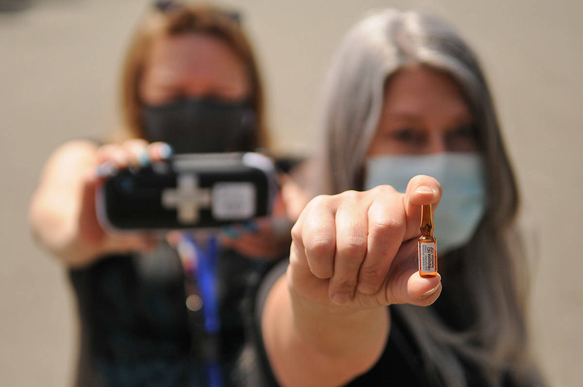 Jodi Higgs (right) holds a vial of naloxone and Christine Christensen holds a kit in the parking lot of the Pacific Community Resources Society in Chilliwack on Thursday, May 20, 2021. The society is offering a number of upcoming events, workshops and videos to help educate friends and family members who have loved ones that are drug users. (Jenna Hauck/ Chilliwack Progress)