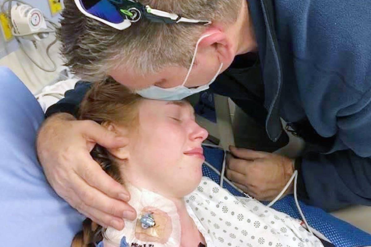Zoë Olson, 19, is hugged by her father Joel Olson in her hospital bed. (Special to The News)