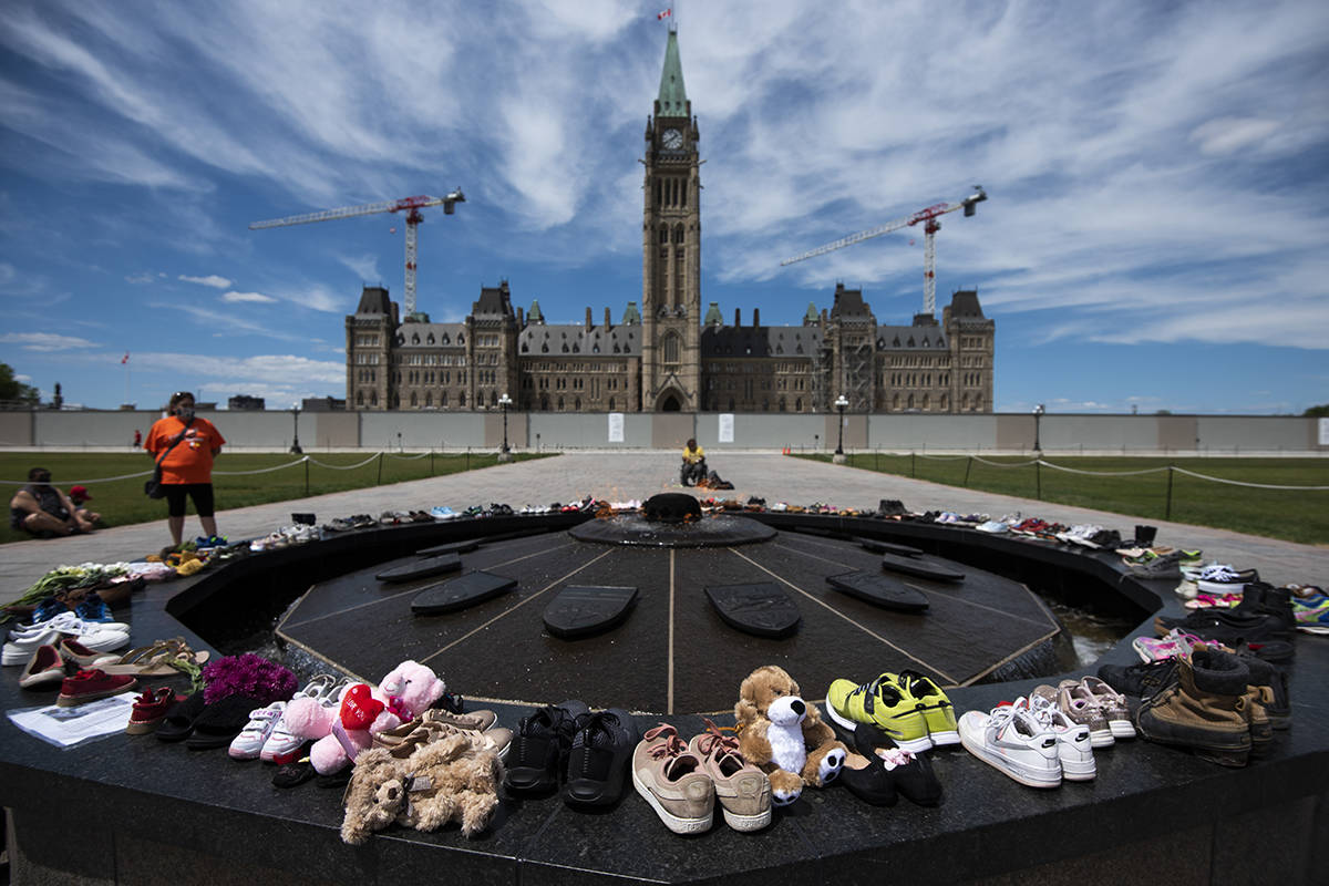 Shoes line the edge of the Centennial Flame on Parliament Hill in memory of the 215 children whose remains were found at the grounds of the former Kamloops Indian Residential School at Tk’emlups te Secwépemc First Nation in Kamloops, B.C., on Sunday, May 30, 2021, THE CANADIAN PRESS/Justin Tang