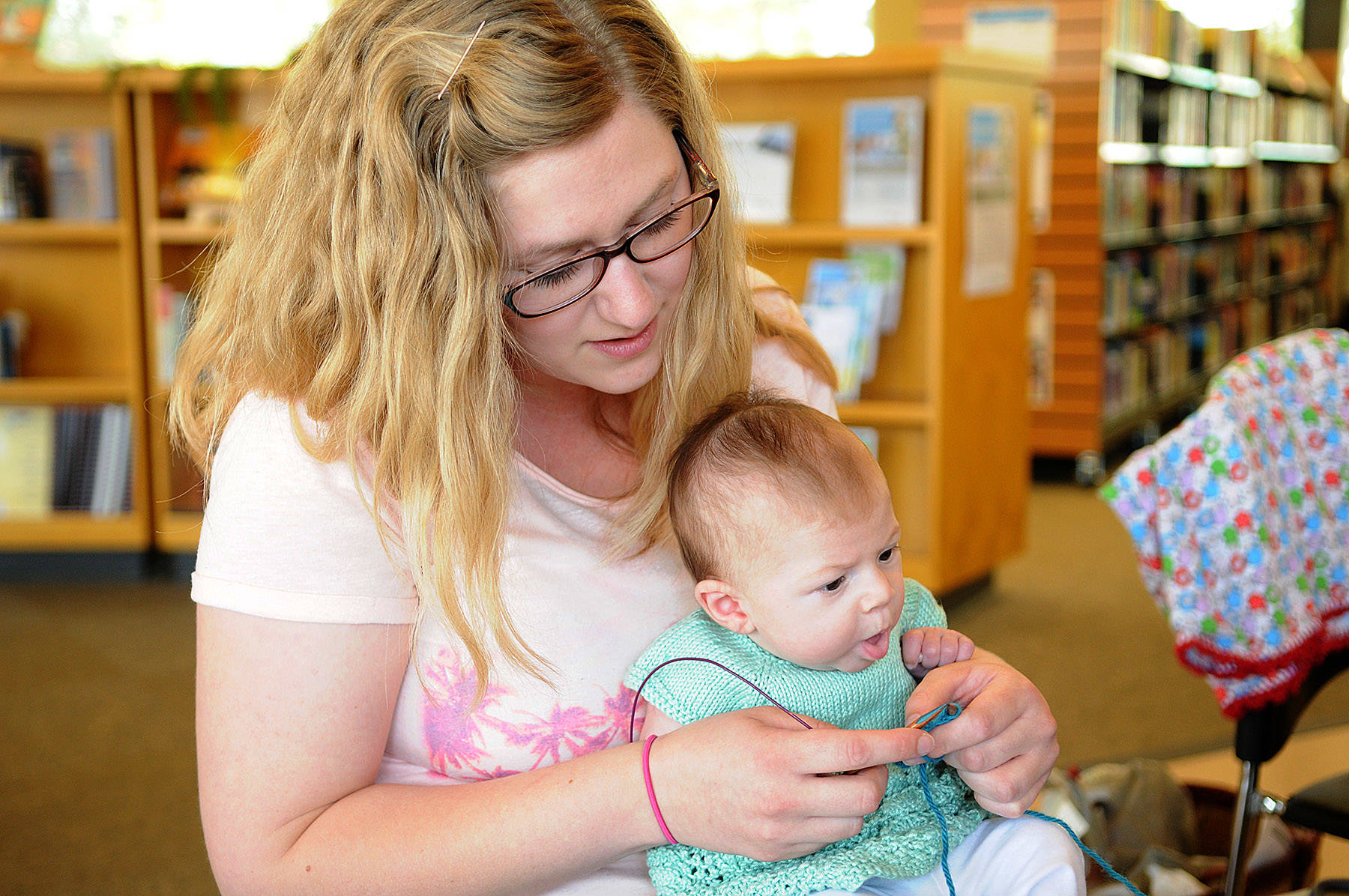 Karen Page knits at the Sardis Library while holding her daughter Rosalie during Worldwide Knit in Public Day on June 17, 2015 in Chilliwack. Saturday, June 12, 2021 is Worldwide Knit in Public Day. (Jenna Hauck/ Chilliwack Progress file)