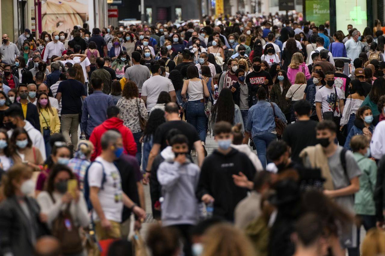 People wearing face masks to protect against the spread of coronavirus walk along a comercial street in downtown Madrid, Spain, Saturday, June 5, 2021. Coronavirus infections, hospitalizations and deaths are plummeting across much of Europe. Vaccination rates are accelerating, and with them, the promise of summer vacations. (AP Photo/Manu Fernandez)