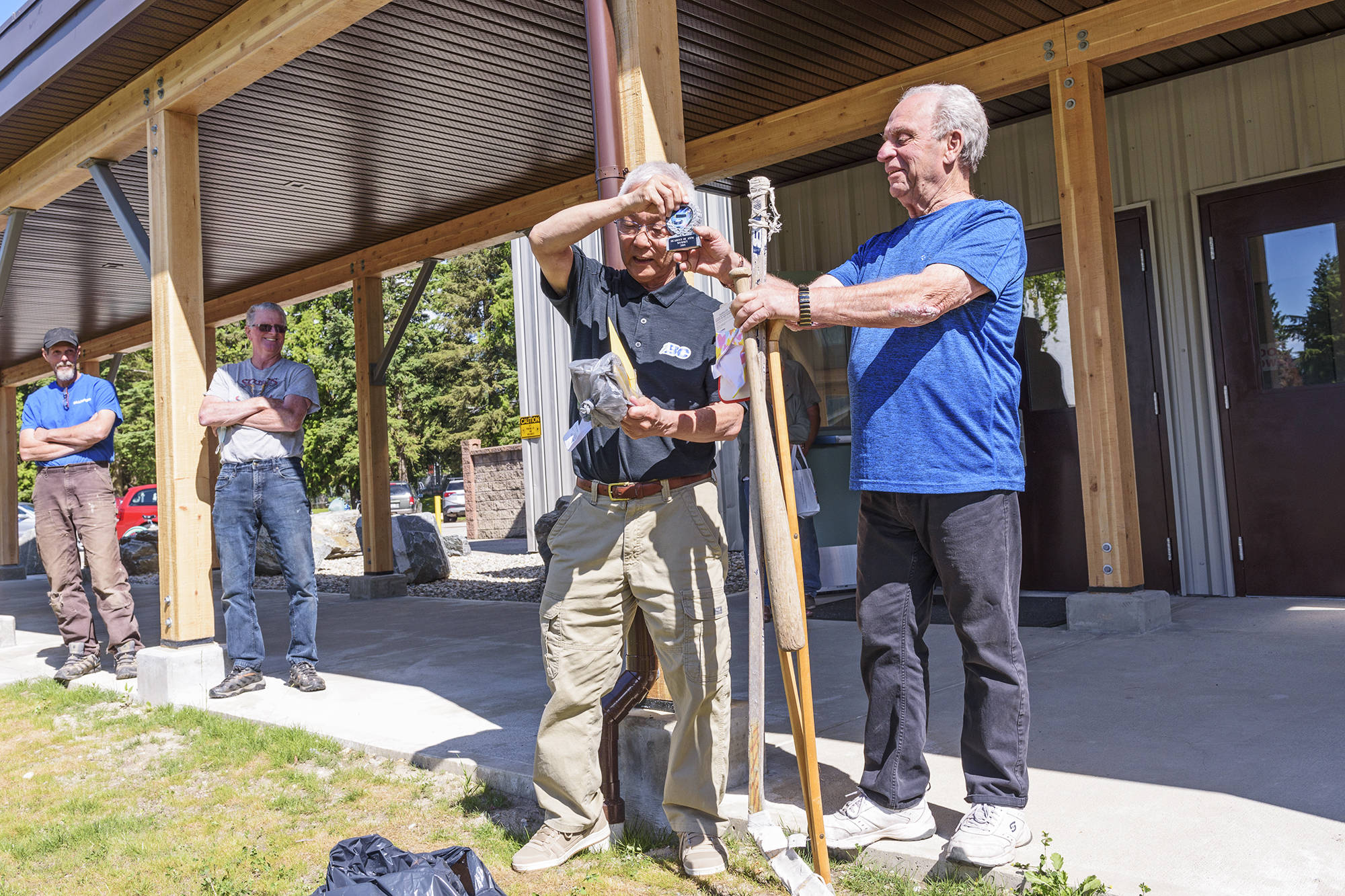 Salmon Arm Minor Hockey’s Roy Sakaki presents Wayne March with some gifts for his retirement, including a crutch and an old hockey stick, during a surprise presentation outside the Sicamous and District Recreation Centre on Thursday, June 10, 2021. (Lachlan Labere-Salmon Arm Observer)