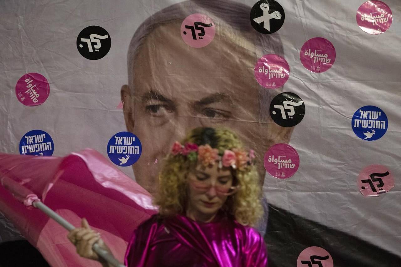 An Israeli protester wears pink during a demonstration against Israeli Prime Minister Benjamin Netanyahu outside his official residence in Jerusalem, Saturday, June 12, 2021. If all goes according to plan, Israel will swear in a new government on Sunday, ending Prime Minister Benjamin Netanyahu’s record 12-year rule and a political crisis that inflicted four elections on the country in less than two years. Hebrew reads: “You failed”,” Israel free” and “Leave”. (AP Photo/Ariel Schalit)