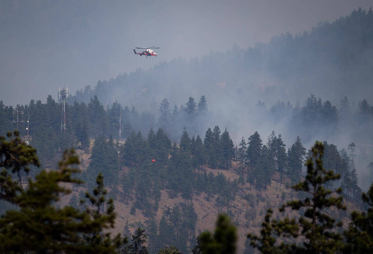 A helicopter pilot prepares to drop water on a wildfire burning in Lytton, B.C., on Friday, July 2, 2021. THE CANADIAN PRESS/Darryl Dyck