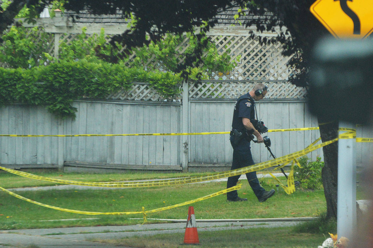 A police officer uses a metal detector at the scene of a Surrey house fire Wednesday afternoon. (Aaron Hinks photo)
