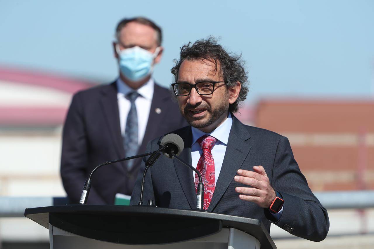 Transport Minister Omar Alghabra speaks while Ottawa South MP David McGuinty looks on during a press conference at the Ottawa MacDonald-Cartier International Airport on Wednesday, June 16, 2021. THE CANADIAN PRESS/David Kawai