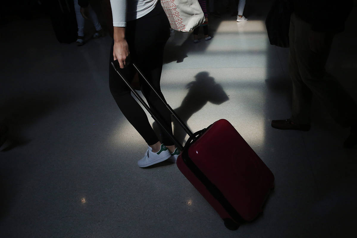 FILE - In this Nov. 27, 2019, file photo a traveler walks through the terminal at the Fort Lauderdale-Hollywood International Airport in Fort Lauderdale, Fla. (AP Photo/Brynn Anderson, File)