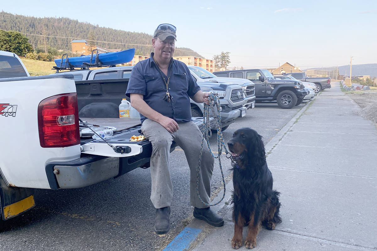 Lone Butte resident Brad Mason waits outside the ESS Centre in Williams Lake Wednesday evening, July 14 with his dog Archie as his wife Victoria registers them as evacuees. (Angie Mindus photo - Williams Lake Tribune)