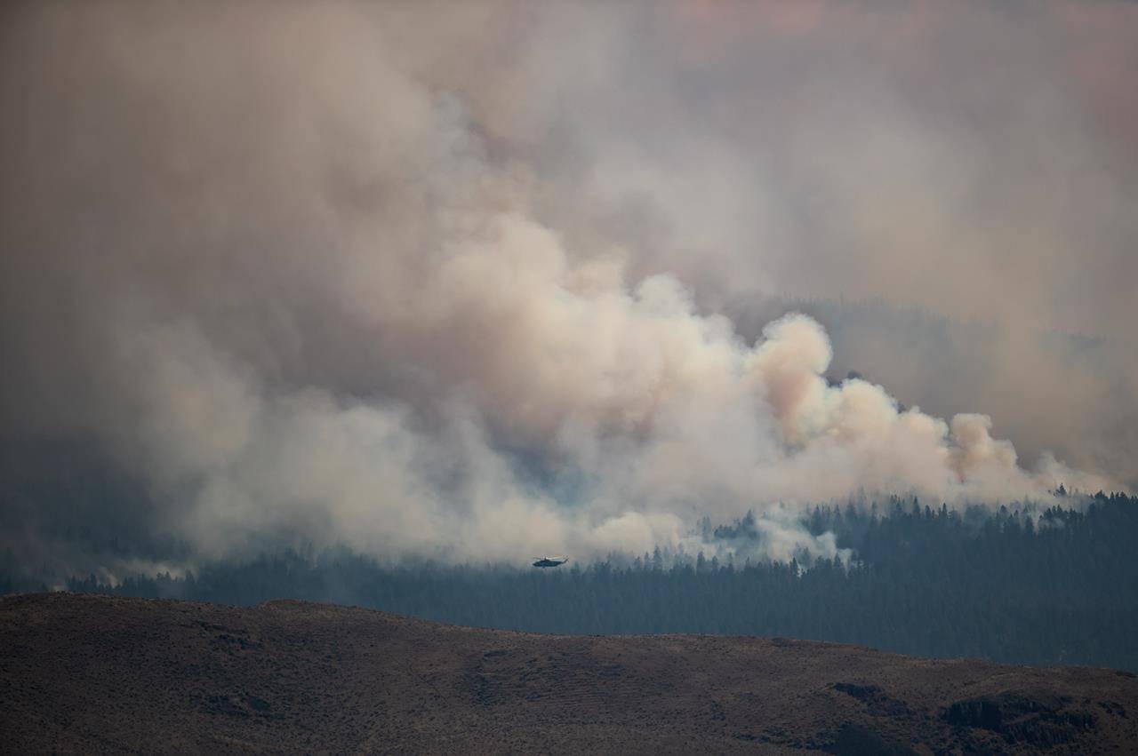 A helicopter flies past the Tremont Creek wildfire burning on the mountains above Ashcroft, B.C., on Friday, July 16, 2021. THE CANADIAN PRESS/Darryl Dyck
