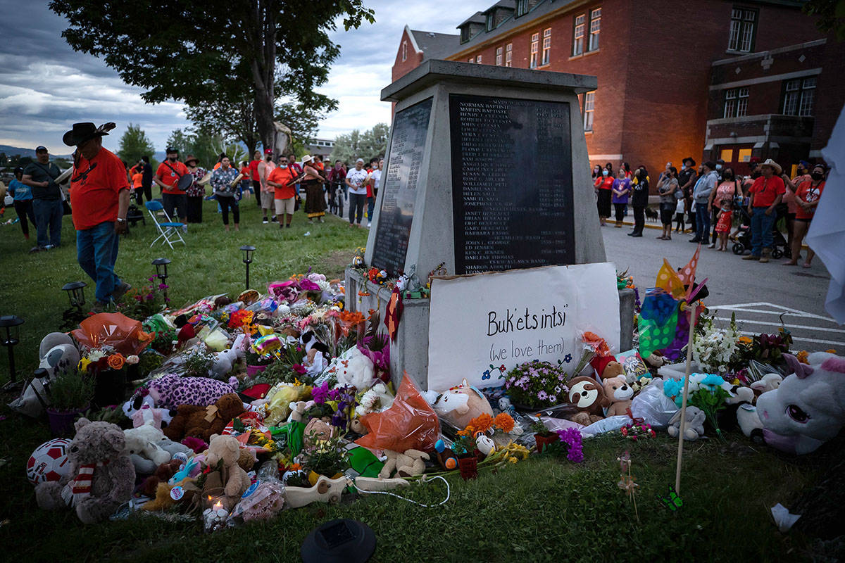 People sing and drum at a memorial outside the former Kamloops Indian Residential School to honour the 215 children whose remains have been discovered buried near the facility, in Kamloops, B.C., on Monday, May 31, 2021. THE CANADIAN PRESS/Darryl Dyck