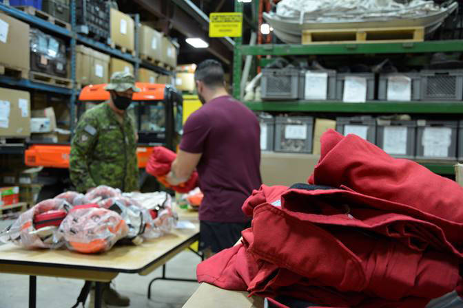 A soldier from 1 Combat Engineer Regiment receives his personal protective equipment, including red fire retardant coveralls, from Land Task Force – Vernon supply prior to proceeding to the fire lines in support of BC Wildfire Service. (Captain Jamie Blois, Public Affairs Officer, Land Task Force – Vernon photo)