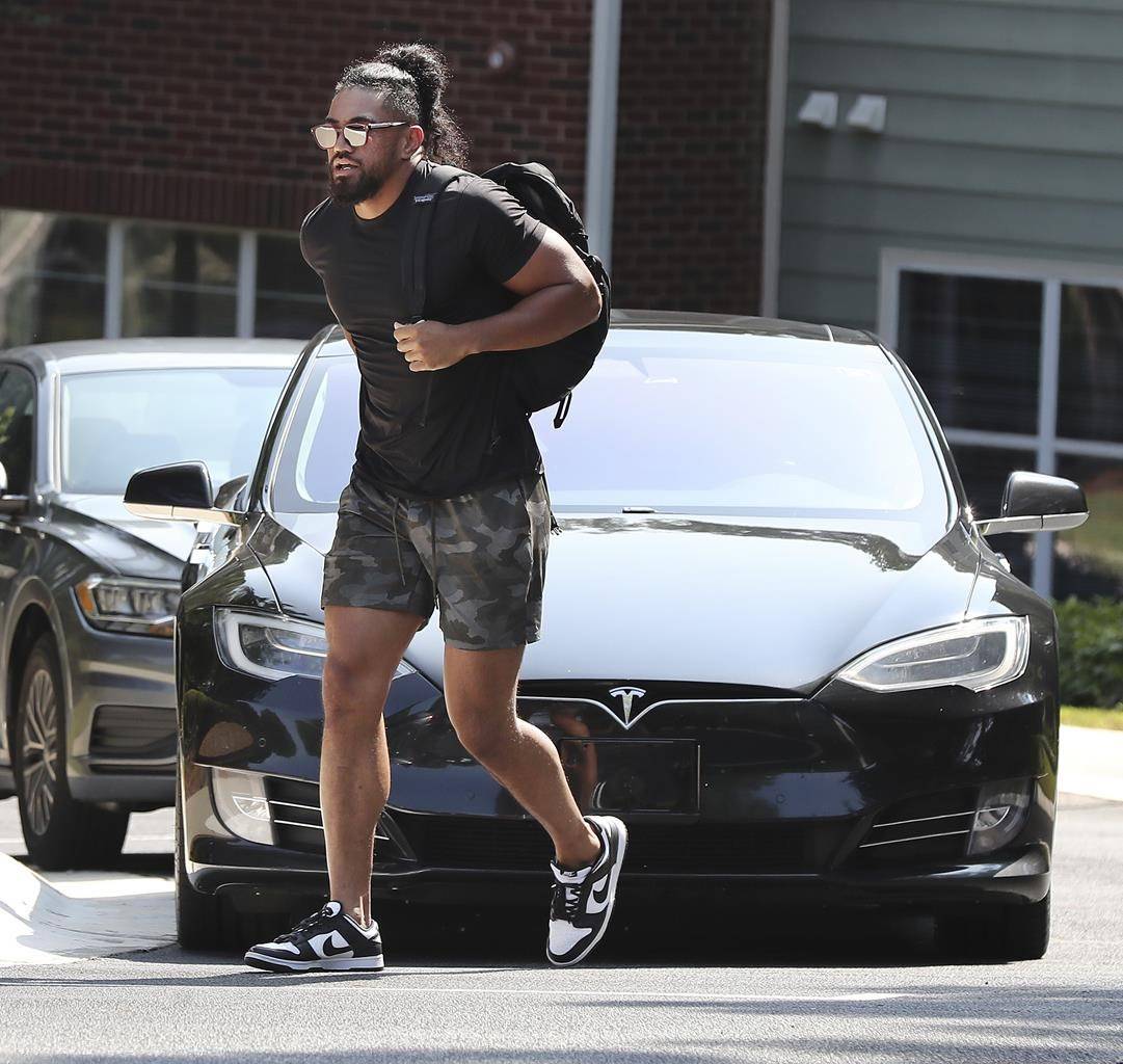 Atlanta Falcons linebacker Jacob Tuioti-Mariner walks in front of the Tesla he arrived in for NFL football training camp in Flowery Branch, Ga., Tuesday, July 27, 2021. (Curtis Compton/Atlanta Journal-Constitution via AP)