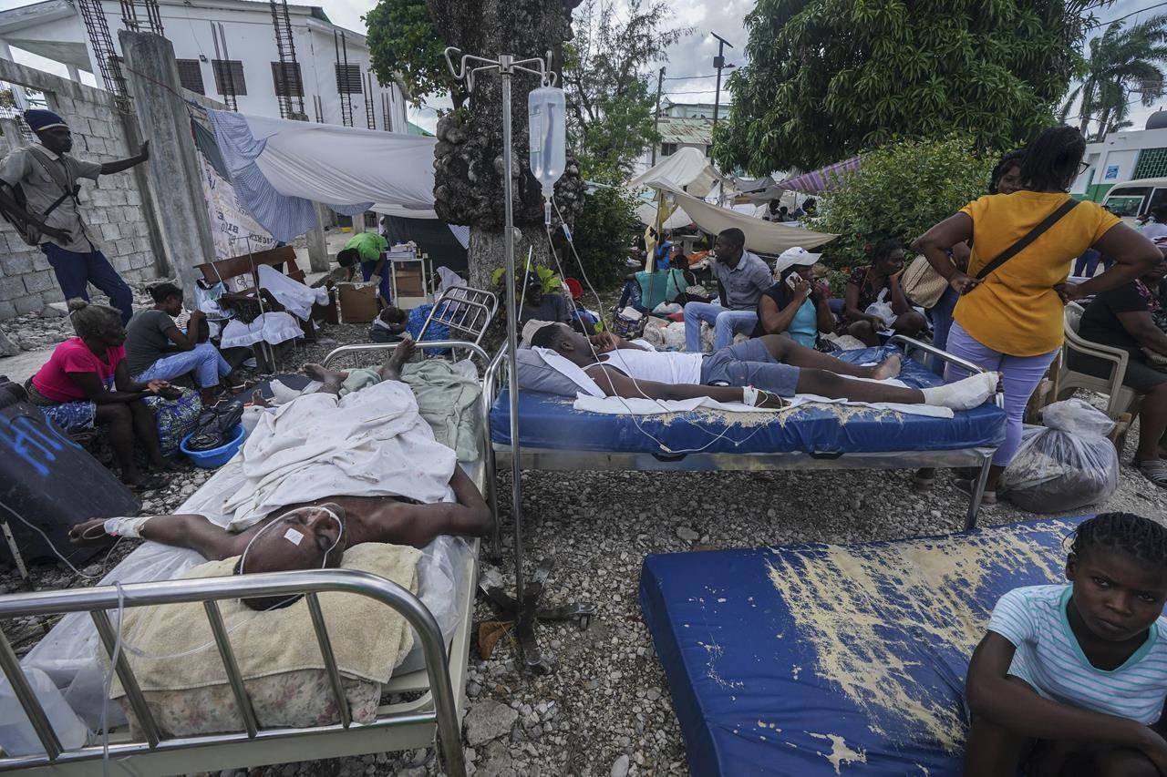 Injured people lie in beds outside the Immaculée Conception hospital in Les Cayes, Haiti, Monday, Aug. 16, 2021, two days after a 7.2-magnitude earthquake struck the southwestern part of the country. (AP Photo/Fernando Llano)